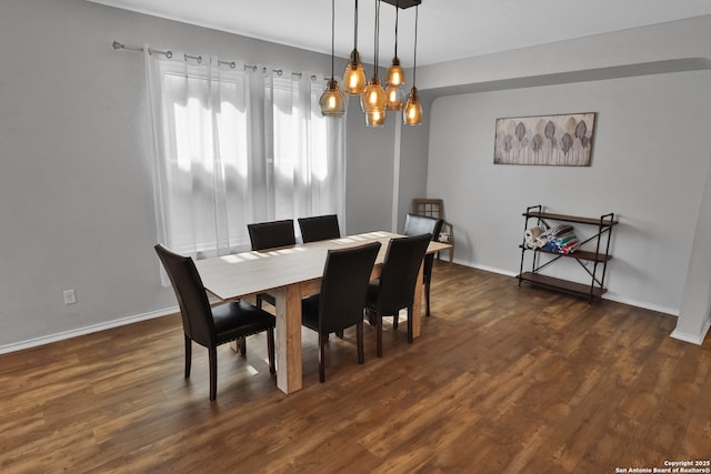 dining area featuring dark wood-type flooring and a notable chandelier