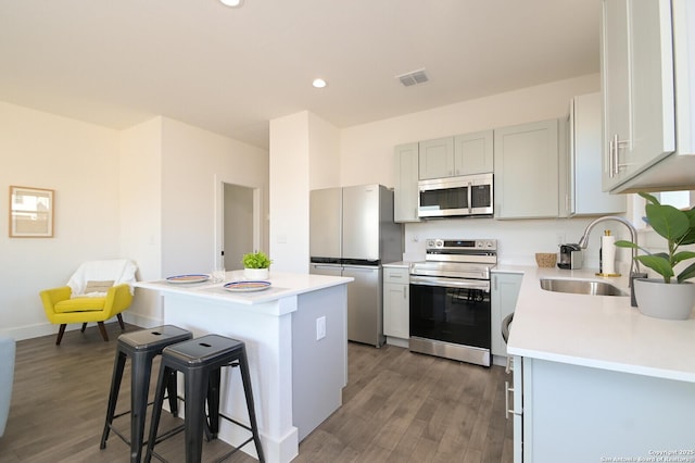 kitchen with stainless steel appliances, dark hardwood / wood-style flooring, a breakfast bar, a center island, and sink