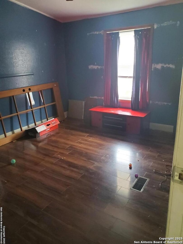 unfurnished room with dark wood-style floors, visible vents, and baseboards