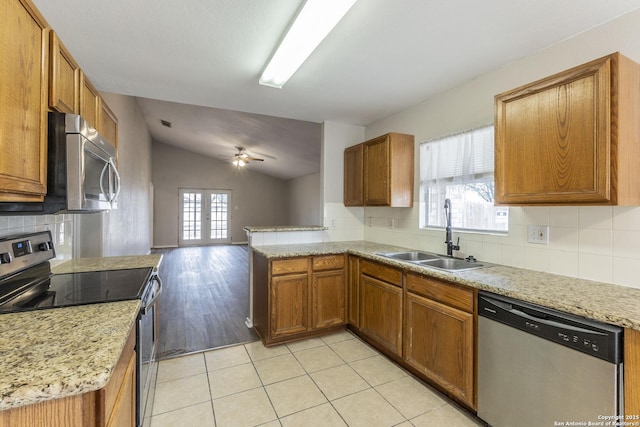 kitchen with french doors, stainless steel appliances, sink, vaulted ceiling, and light tile patterned floors