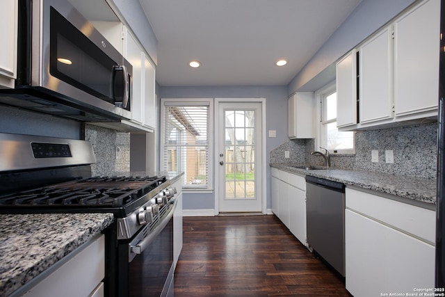 kitchen featuring appliances with stainless steel finishes, white cabinetry, light stone counters, and sink