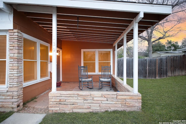 patio terrace at dusk featuring a lawn