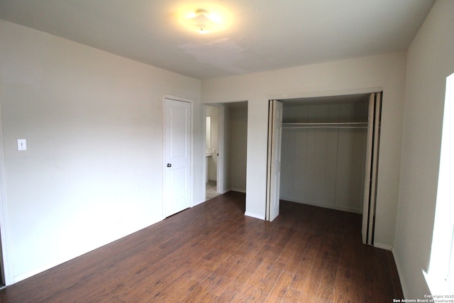 unfurnished bedroom with dark wood-type flooring and a closet