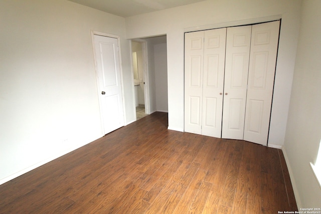 unfurnished bedroom with dark wood-type flooring and a closet