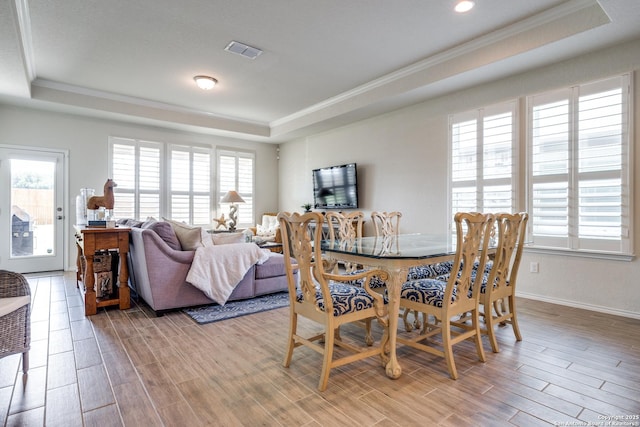 dining area with a tray ceiling, wood finish floors, and visible vents