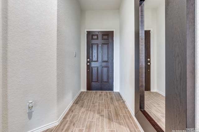 interior space featuring wood finish floors, a textured wall, and baseboards