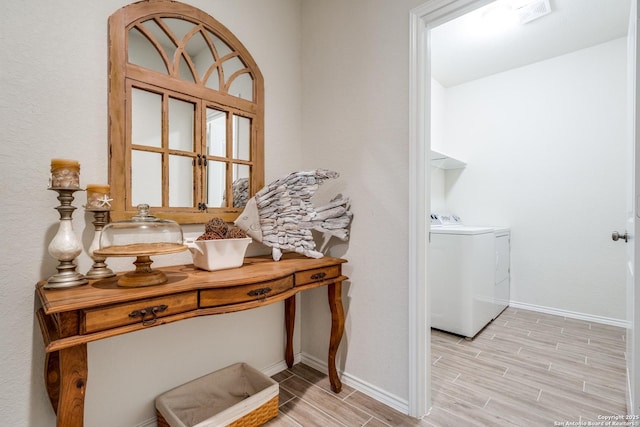 interior space featuring baseboards, laundry area, washer and clothes dryer, and wood tiled floor