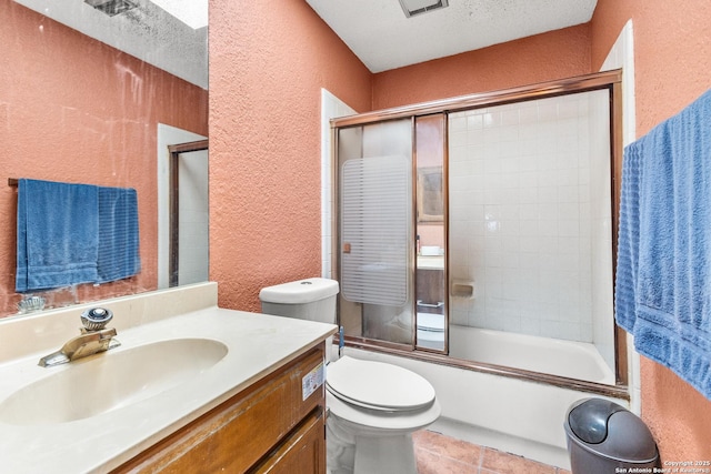 full bathroom with vanity, bath / shower combo with glass door, toilet, and a textured ceiling