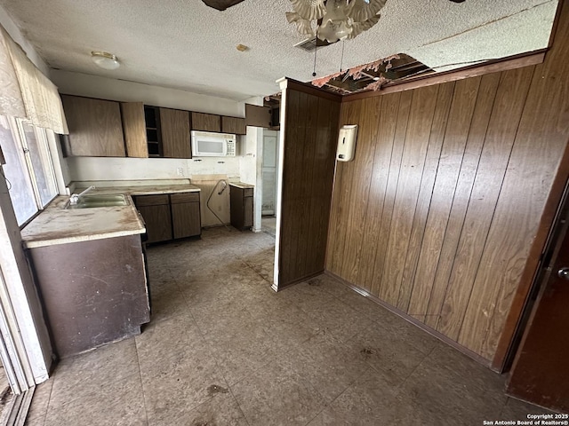 kitchen with sink, wood walls, and a textured ceiling