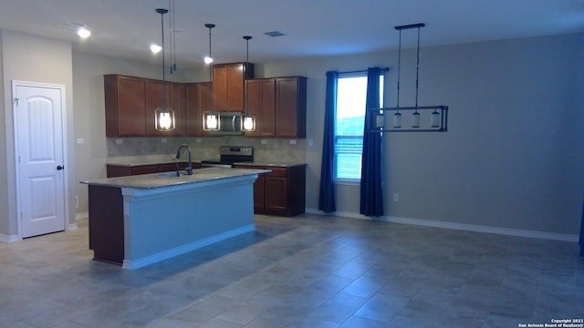 kitchen with sink, appliances with stainless steel finishes, a kitchen island with sink, and hanging light fixtures