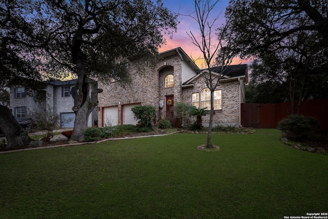 view of front of property featuring a garage, brick siding, a front yard, and fence