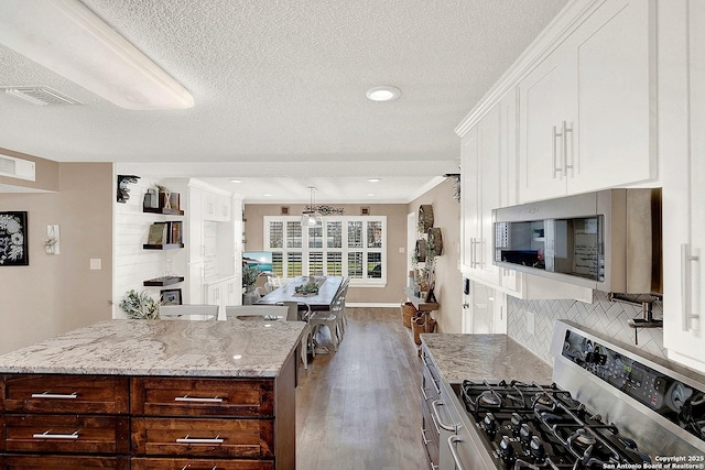 kitchen featuring hardwood / wood-style flooring, stainless steel appliances, light stone countertops, white cabinets, and backsplash