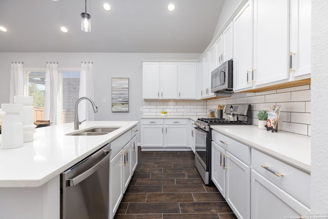 kitchen featuring decorative backsplash, appliances with stainless steel finishes, white cabinets, and a sink