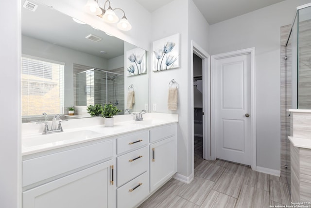 bathroom featuring double vanity, a shower stall, visible vents, and a sink