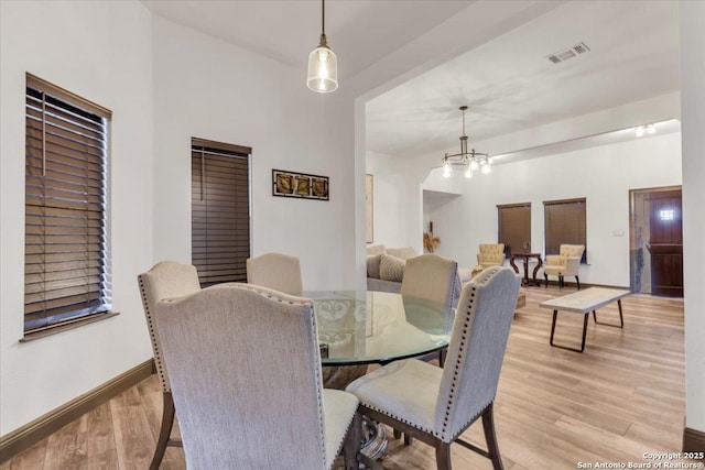 dining space featuring light wood-type flooring and an inviting chandelier