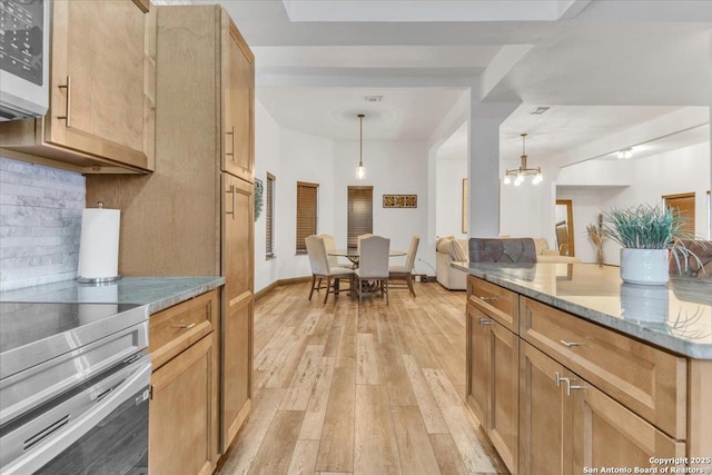 kitchen featuring light hardwood / wood-style flooring, tasteful backsplash, light stone counters, appliances with stainless steel finishes, and pendant lighting