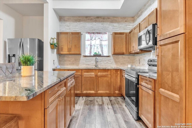 kitchen with sink, stainless steel appliances, backsplash, and light stone counters