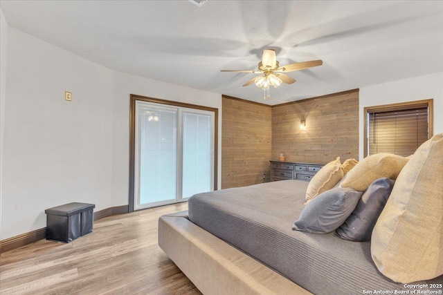 bedroom featuring light wood-type flooring, ceiling fan, access to outside, and wood walls