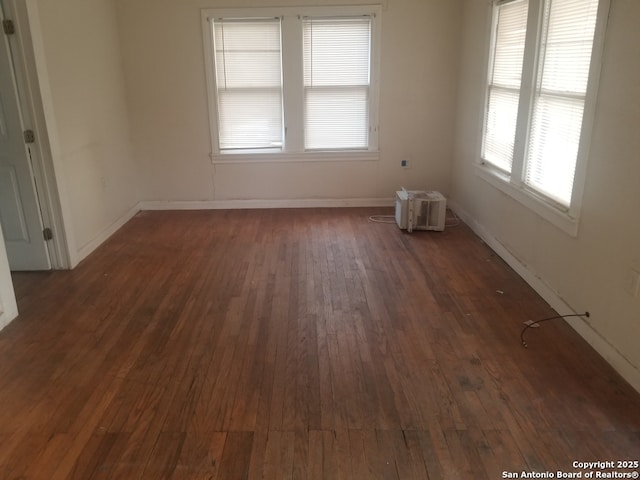 unfurnished room with a wall mounted AC and dark hardwood / wood-style floors