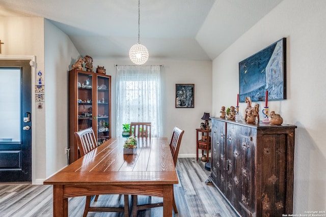 dining space with light wood-type flooring and lofted ceiling