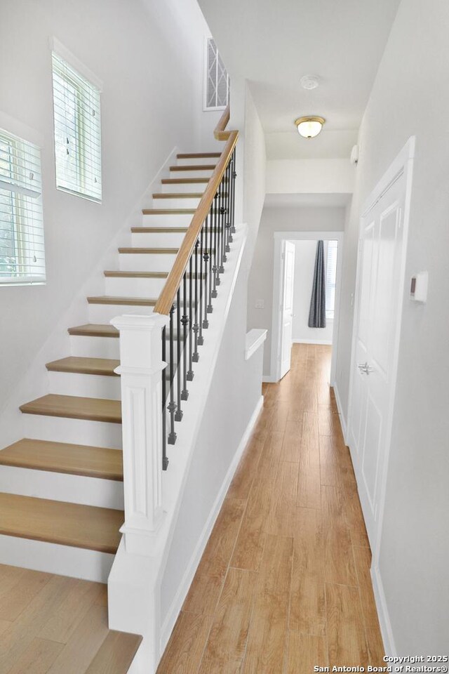 corridor with visible vents, stairway, wood finished floors, and a healthy amount of sunlight