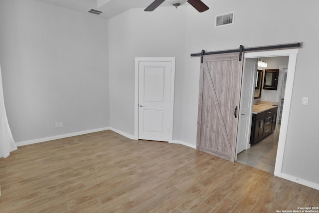 unfurnished bedroom with a towering ceiling, visible vents, and light wood-type flooring