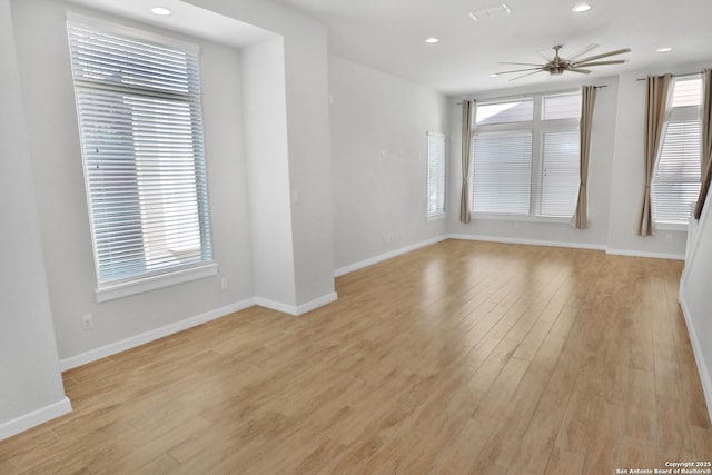 unfurnished room with a wealth of natural light, light wood finished floors, baseboards, and a ceiling fan