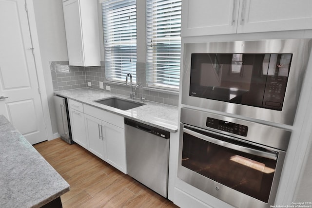 kitchen featuring stainless steel appliances, tasteful backsplash, white cabinetry, and a sink