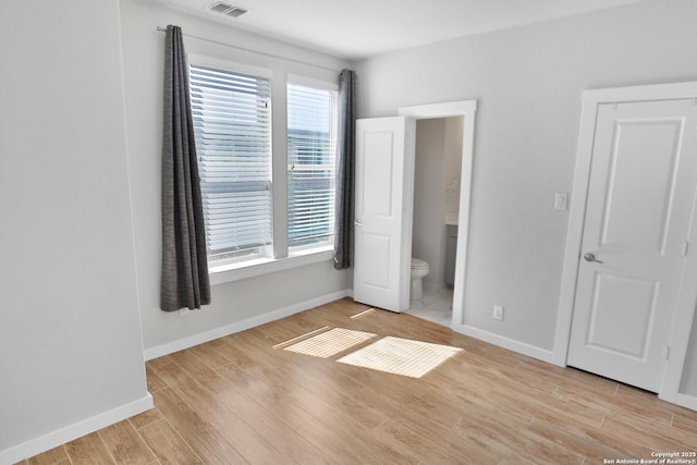 unfurnished bedroom featuring visible vents, light wood-type flooring, baseboards, and ensuite bathroom
