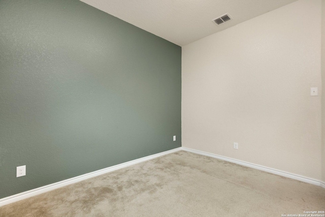 empty room featuring baseboards, visible vents, and light colored carpet