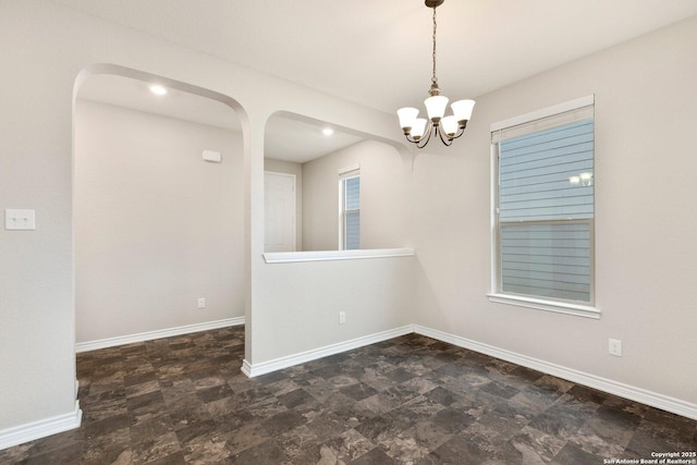 empty room featuring stone finish flooring, baseboards, and a chandelier