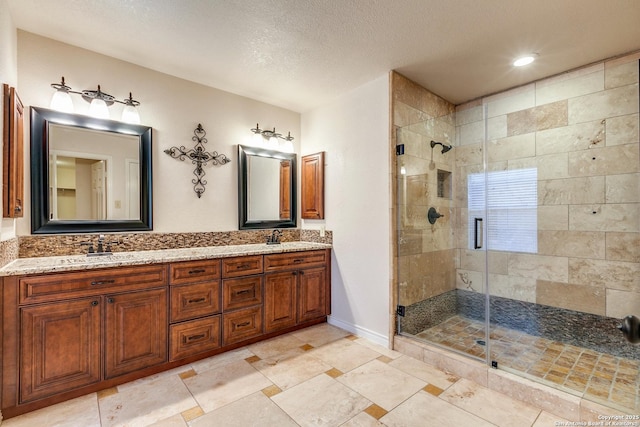 bathroom with a textured ceiling, a shower with door, and vanity