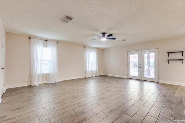 empty room featuring ceiling fan, light hardwood / wood-style flooring, french doors, and a healthy amount of sunlight