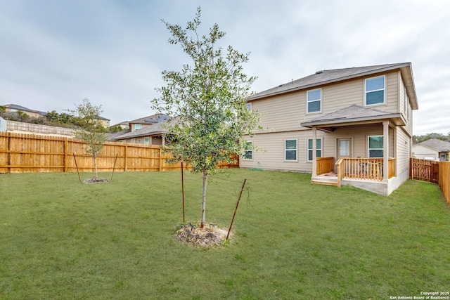 rear view of house featuring a lawn and a fenced backyard