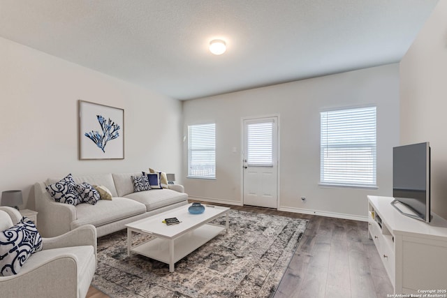 living area with a textured ceiling, hardwood / wood-style flooring, and baseboards