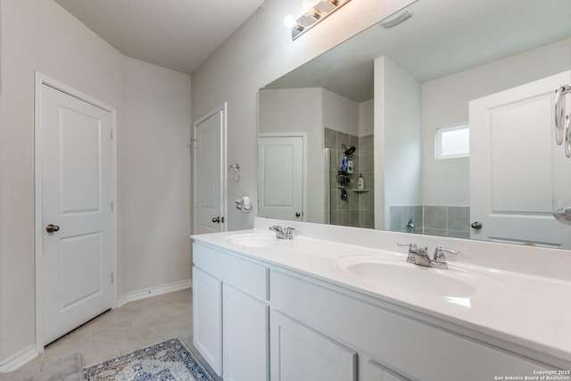 full bath featuring tile patterned floors, tiled shower, a sink, and double vanity