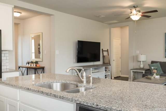 kitchen with sink, ceiling fan, white cabinets, and light stone counters