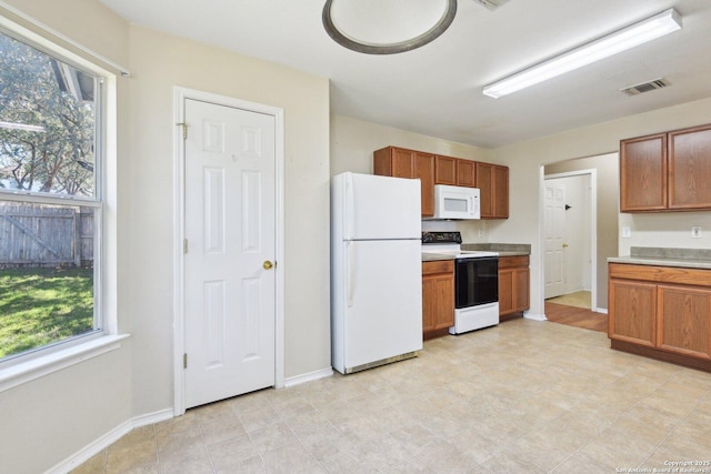 kitchen featuring light countertops, visible vents, brown cabinetry, white appliances, and baseboards