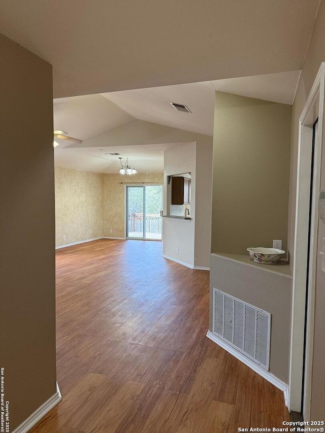 unfurnished room featuring a chandelier, wood-type flooring, and lofted ceiling