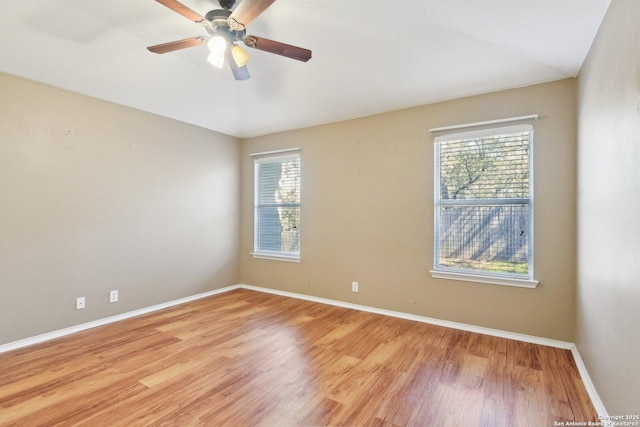 unfurnished room with light wood finished floors, a ceiling fan, a wealth of natural light, and baseboards