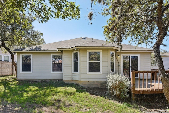 back of house featuring a lawn, a wooden deck, and fence