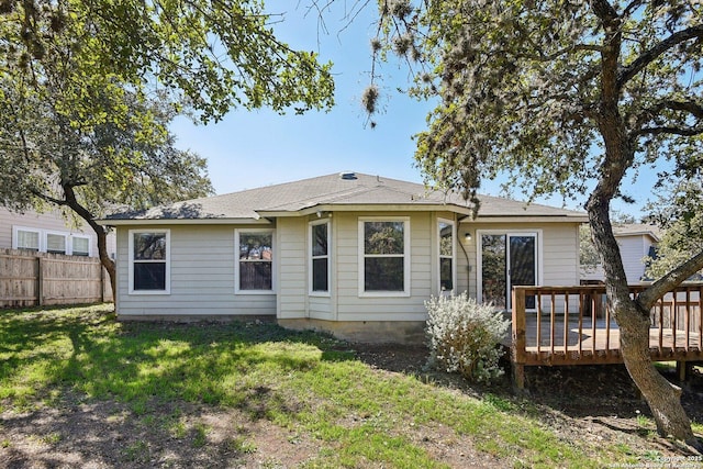 back of property featuring a deck, a lawn, and fence