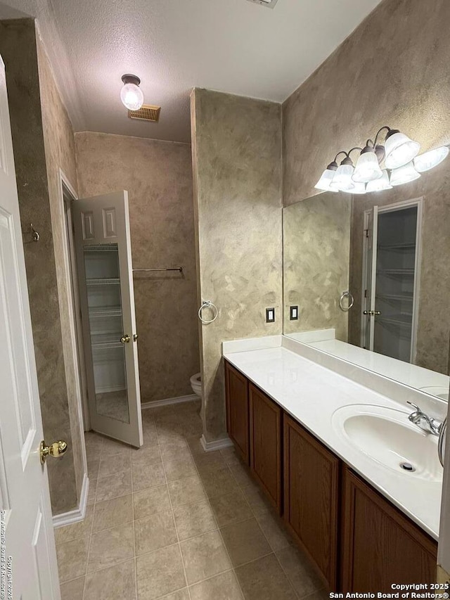 bathroom featuring toilet, a textured ceiling, tile patterned flooring, and vanity