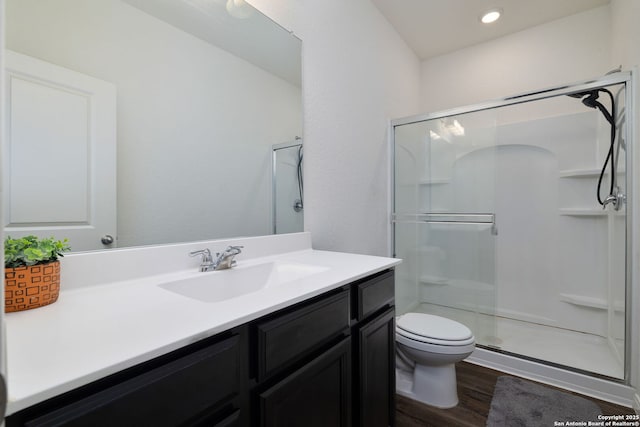 bathroom with hardwood / wood-style floors, toilet, an enclosed shower, and vanity