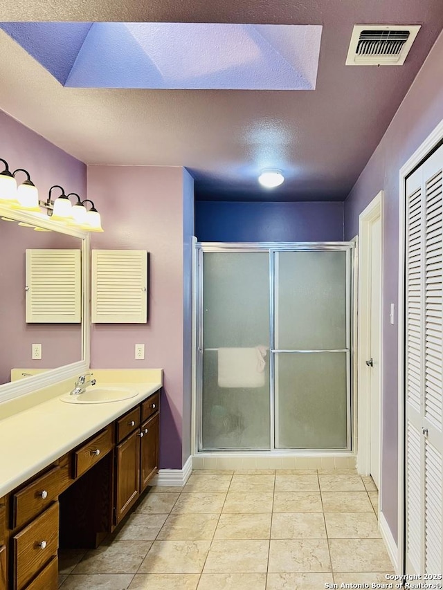 bathroom with a textured ceiling, vanity, tile patterned flooring, and an enclosed shower