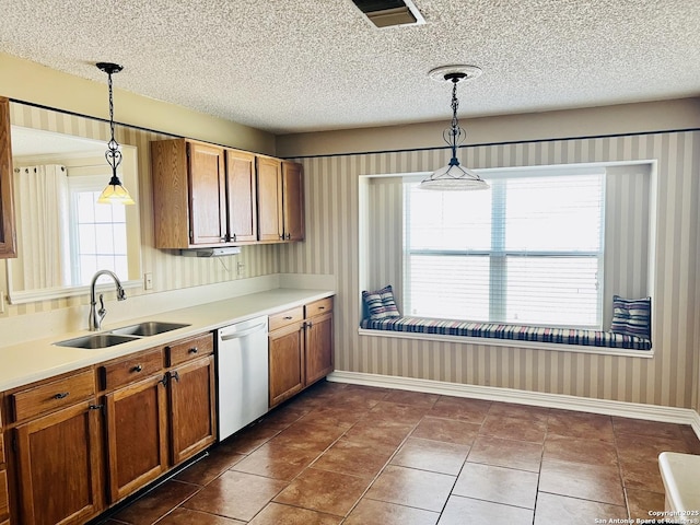 kitchen featuring sink, dishwasher, a textured ceiling, decorative light fixtures, and dark tile patterned floors