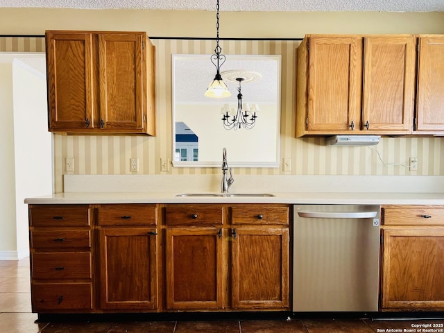 kitchen with hanging light fixtures, dishwasher, a textured ceiling, dark tile patterned floors, and sink