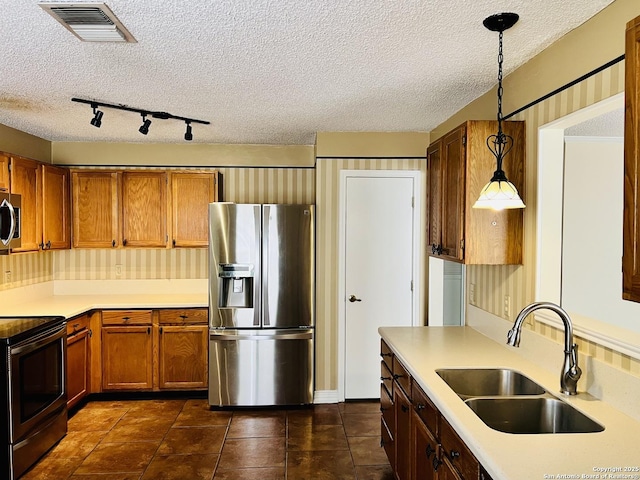 kitchen with stainless steel appliances, dark tile patterned flooring, a textured ceiling, pendant lighting, and sink