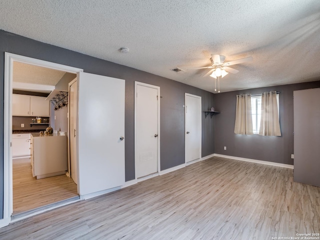 unfurnished bedroom featuring ceiling fan, light hardwood / wood-style flooring, and a textured ceiling