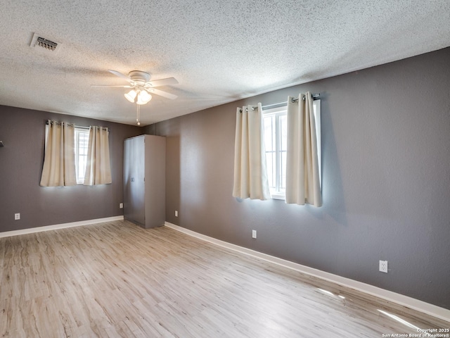 unfurnished room with ceiling fan, light hardwood / wood-style flooring, and a textured ceiling